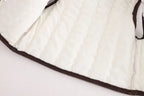 Soft white quilted baby vest with brown trim, cozy infant outerwear