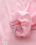 Soft pink children's shirt sleeve with ruffled cuff and white button detail