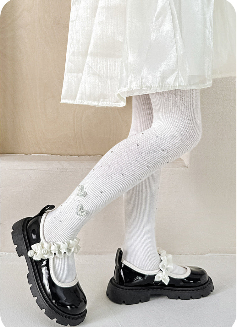 White ribbed tights with heart embellishments, paired with black patent Mary Jane shoes and a white dress.