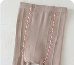 Soft beige kids leggings with ribbed texture and pink dashed seam details, ideal for comfortable everyday wear.