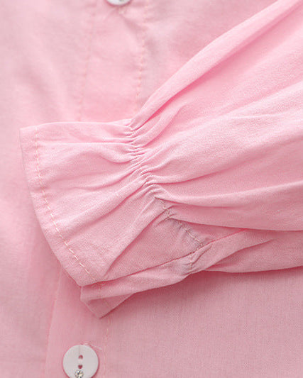 Pink children's blouse with ruffled sleeve detail and button closure, soft fabric for comfort