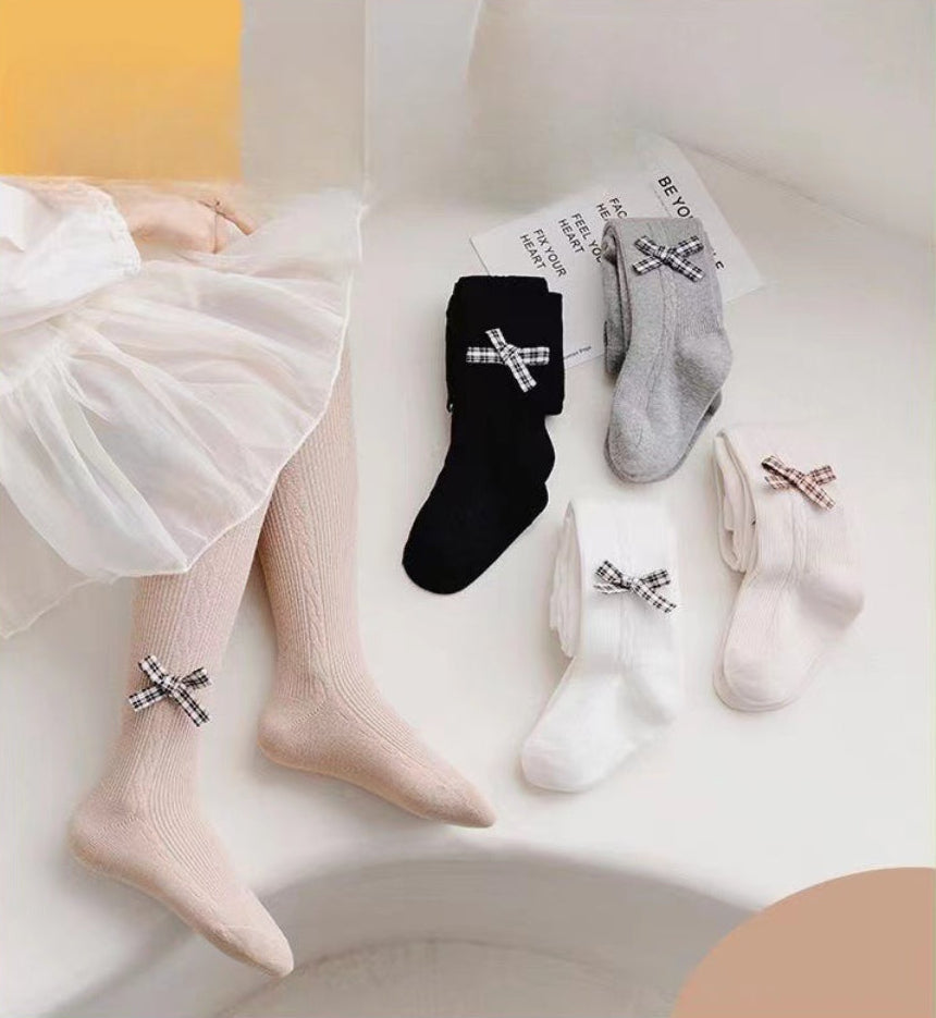 Kids' knee-high socks with plaid bows in black, gray, white, and beige, styled with a tulle skirt for toddler fashion.