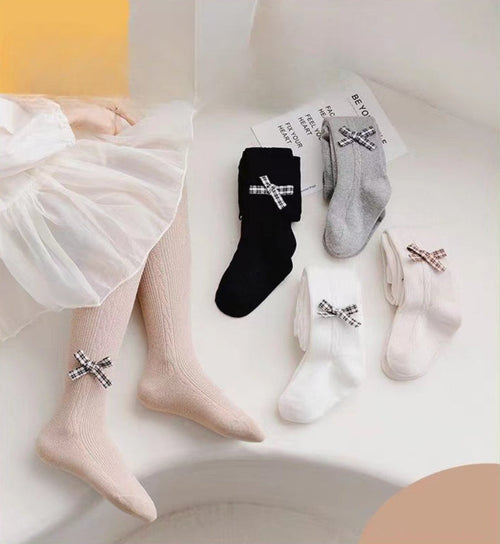 Kids' knee-high socks with plaid bows in black, gray, white, and beige, styled with a tulle skirt for toddler fashion.
