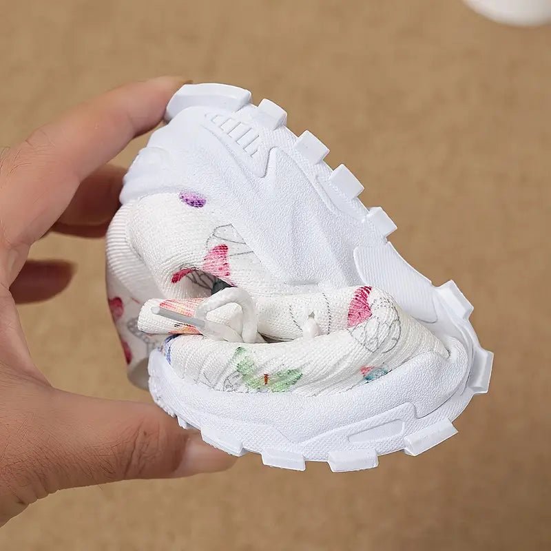 niña con zapatillas deportivas estampado de mariposas jugando